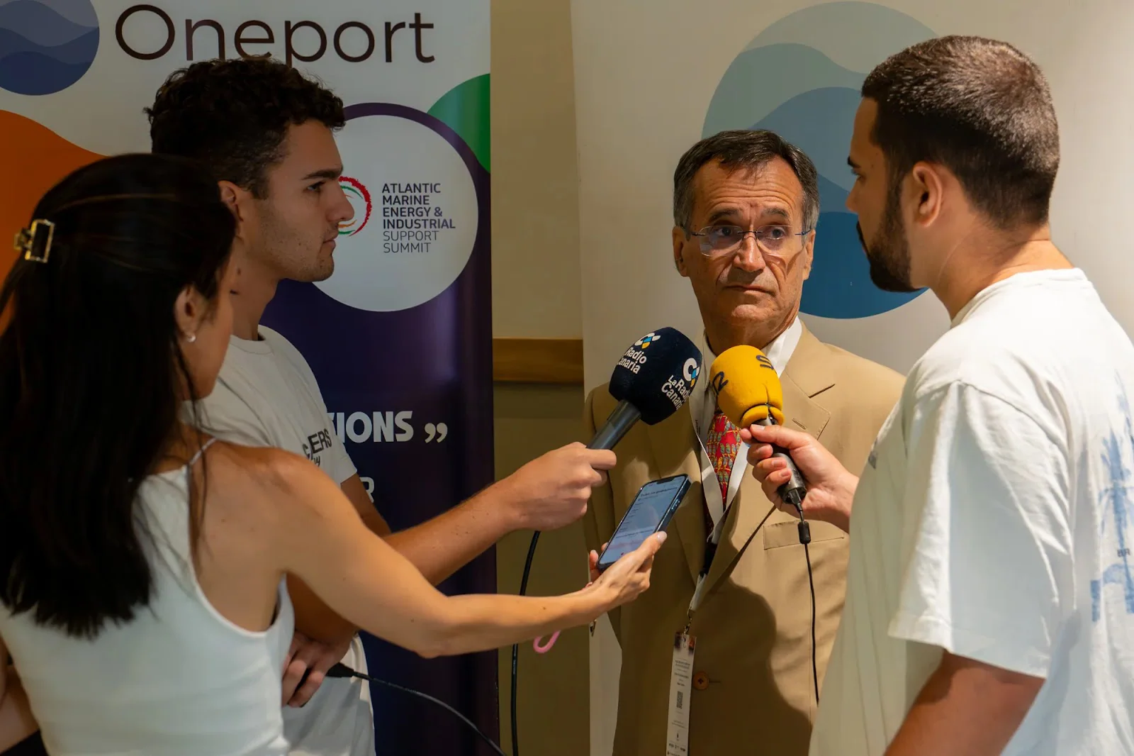 Canarian radio interviews a delegate beside the summit banner